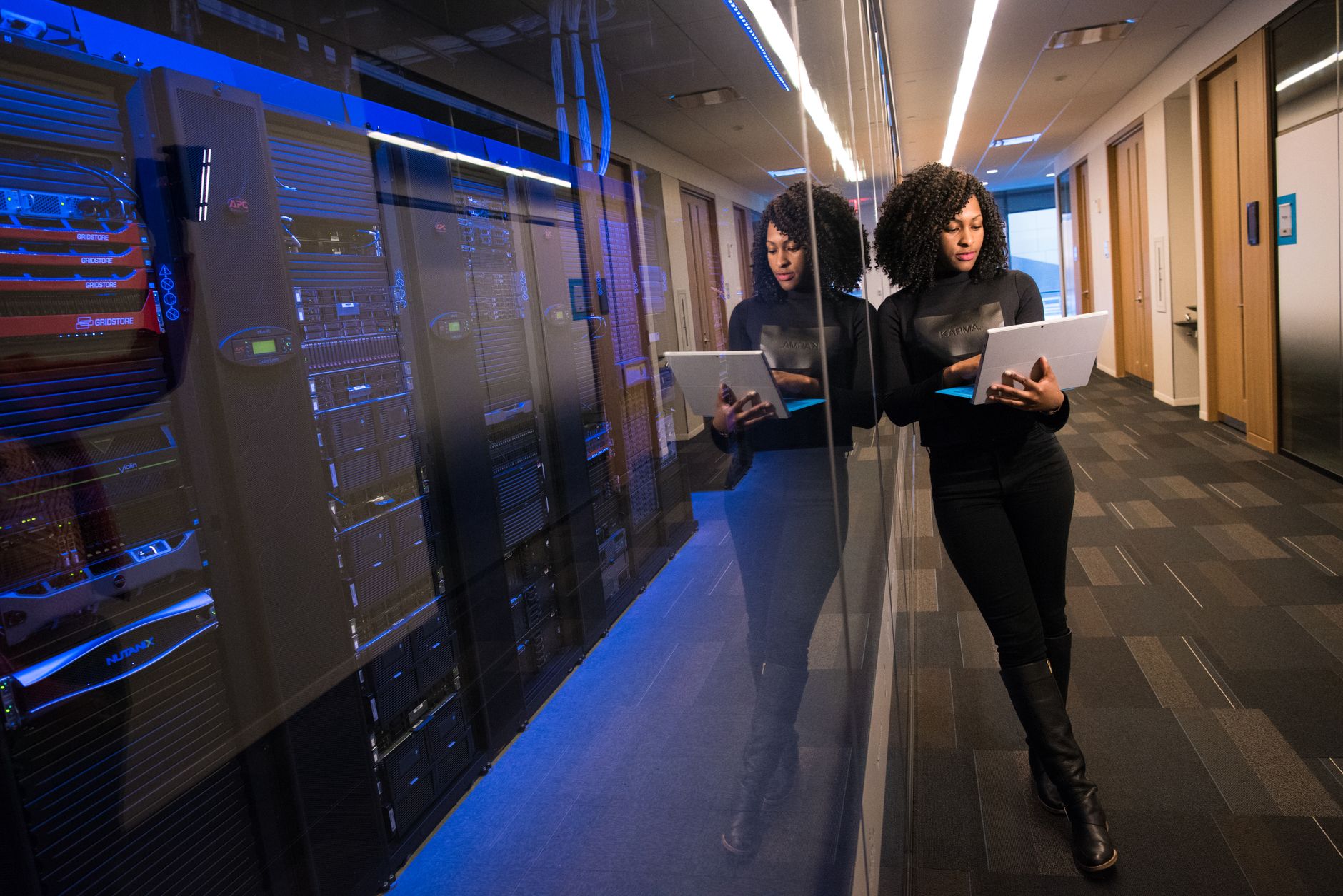 A professional reviewing a laptop beside a clean, modern server room