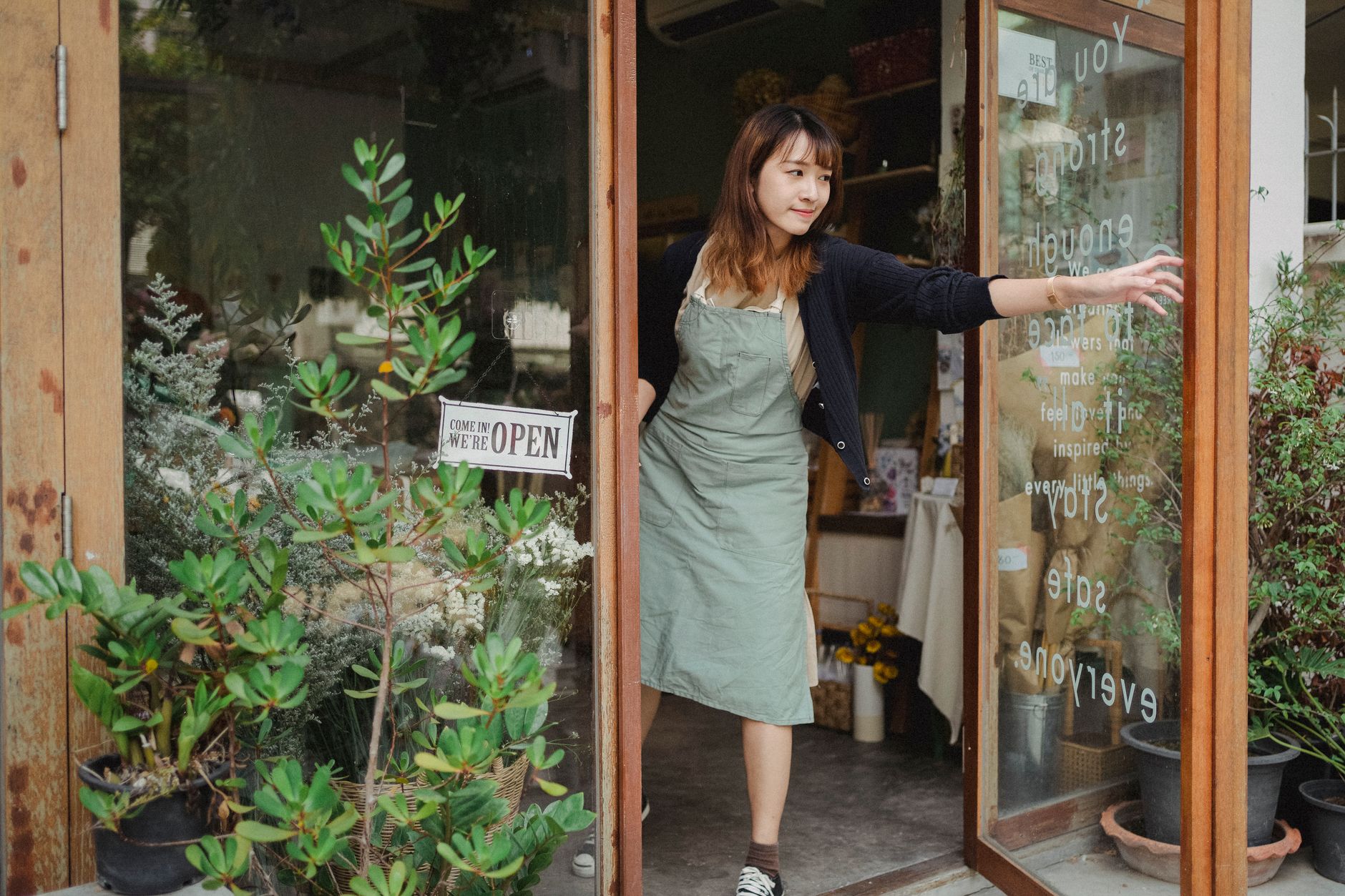 A small business owner opening the glass door of her shop for the day